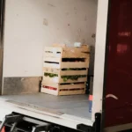 Peti kayu berisi sayuran segar yang dimuat ke dalam truk pengiriman, menggambarkan rantai distribusi pangan dari ladang ke konsumen